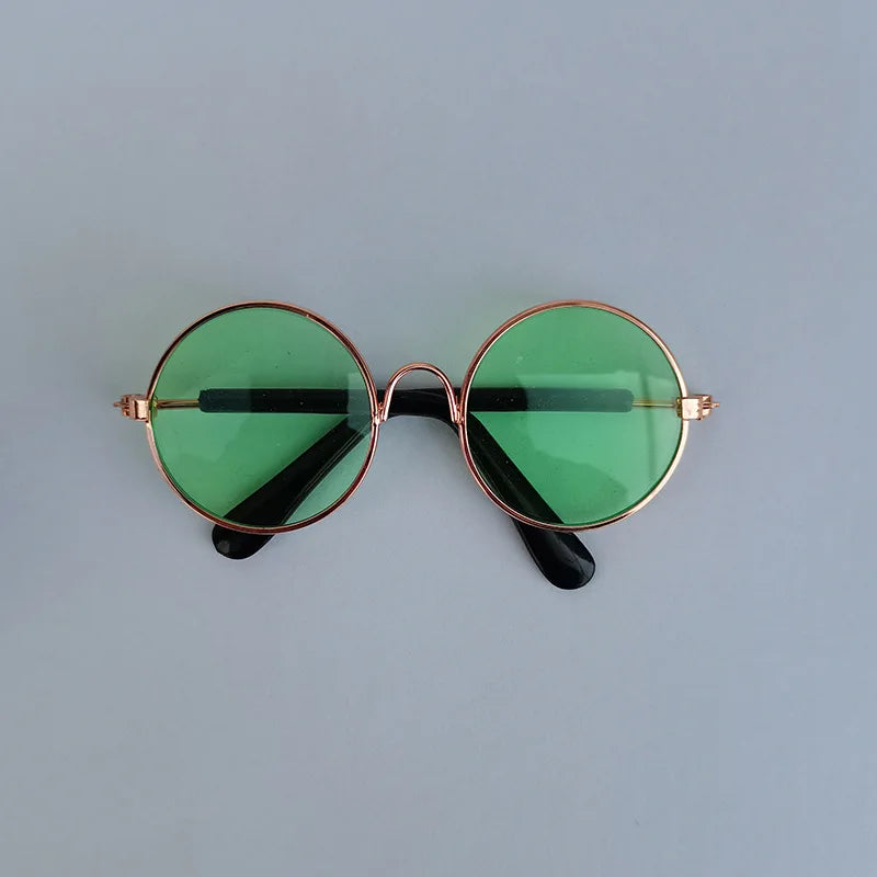Round sunglasses with green lenses and gold frames on a light gray background