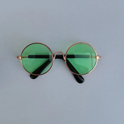 Round sunglasses with green lenses and gold frames on a light gray background
