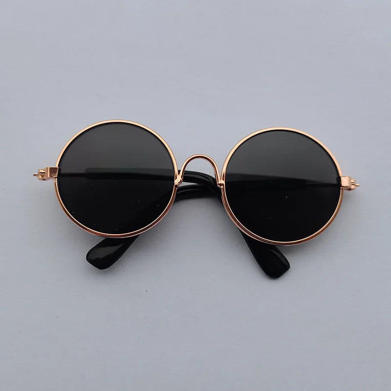 Round sunglasses with black lenses and rose gold frames on a gray background
