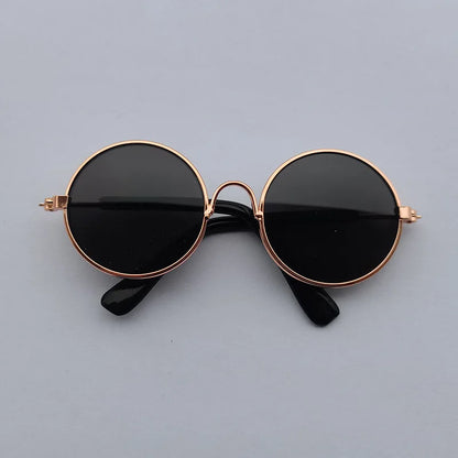 Round sunglasses with black lenses and rose gold frames on a gray background