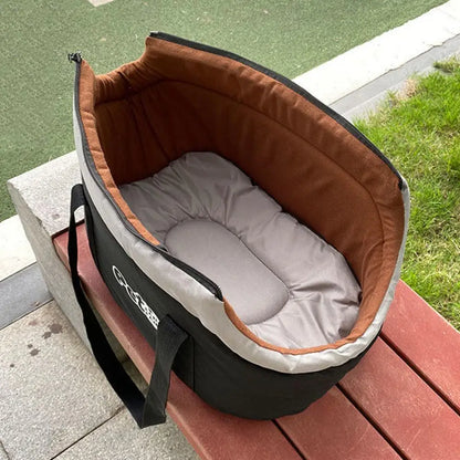 Baby bassinet with brown and gray interior on a wooden surface outdoors