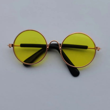 Round sunglasses with yellow lenses and rose gold frames on a light gray background