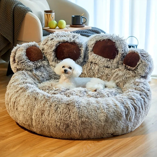 Fluffy dog bed shaped like a paw with a small white dog inside, in a cozy living room setting.