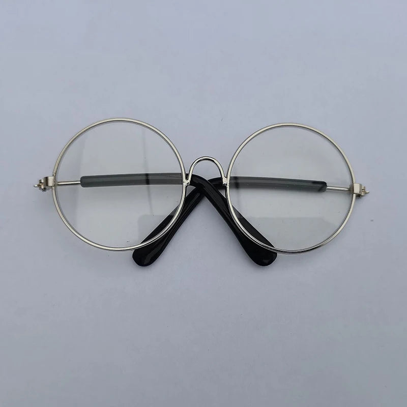Round eyeglasses with gold frame and black arms on a light gray background