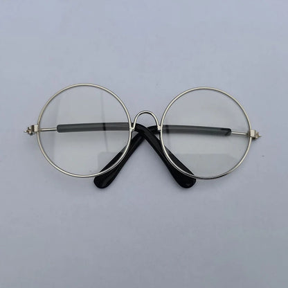 Round eyeglasses with gold frame and black arms on a light gray background