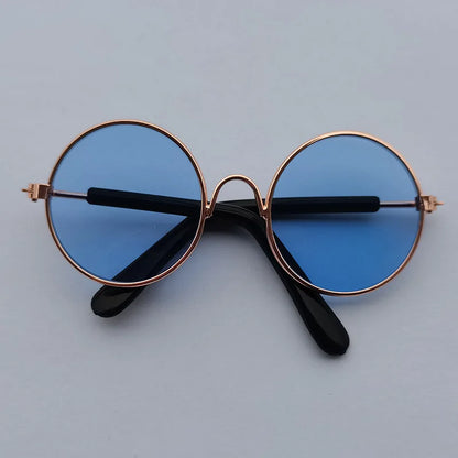Round sunglasses with blue lenses and gold frames on a light gray background