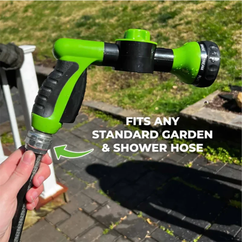 Green and black garden hose nozzle held by a hand with grass and pavement in the background.