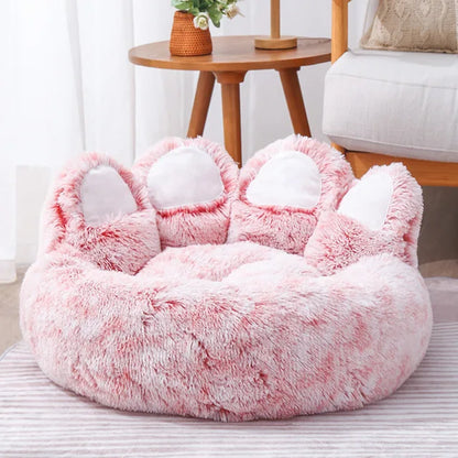Fluffy pink pet bed with cat ears on a striped surface.