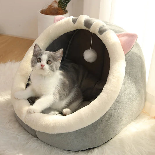 Cat lying in a gray pet bed with pink accents on a soft surface.