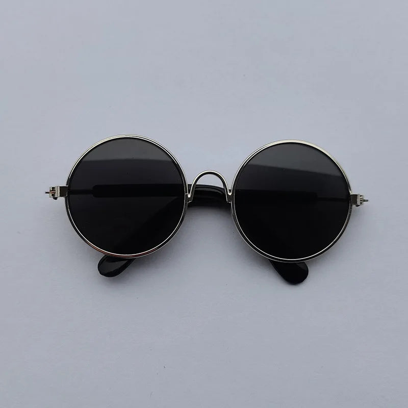 Round sunglasses with black lenses and thin metal frame on a light gray background