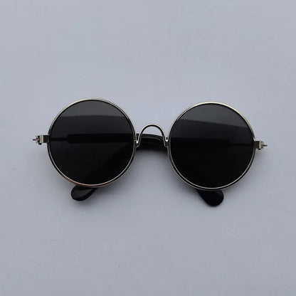 Round sunglasses with black lenses and thin metal frame on a light gray background