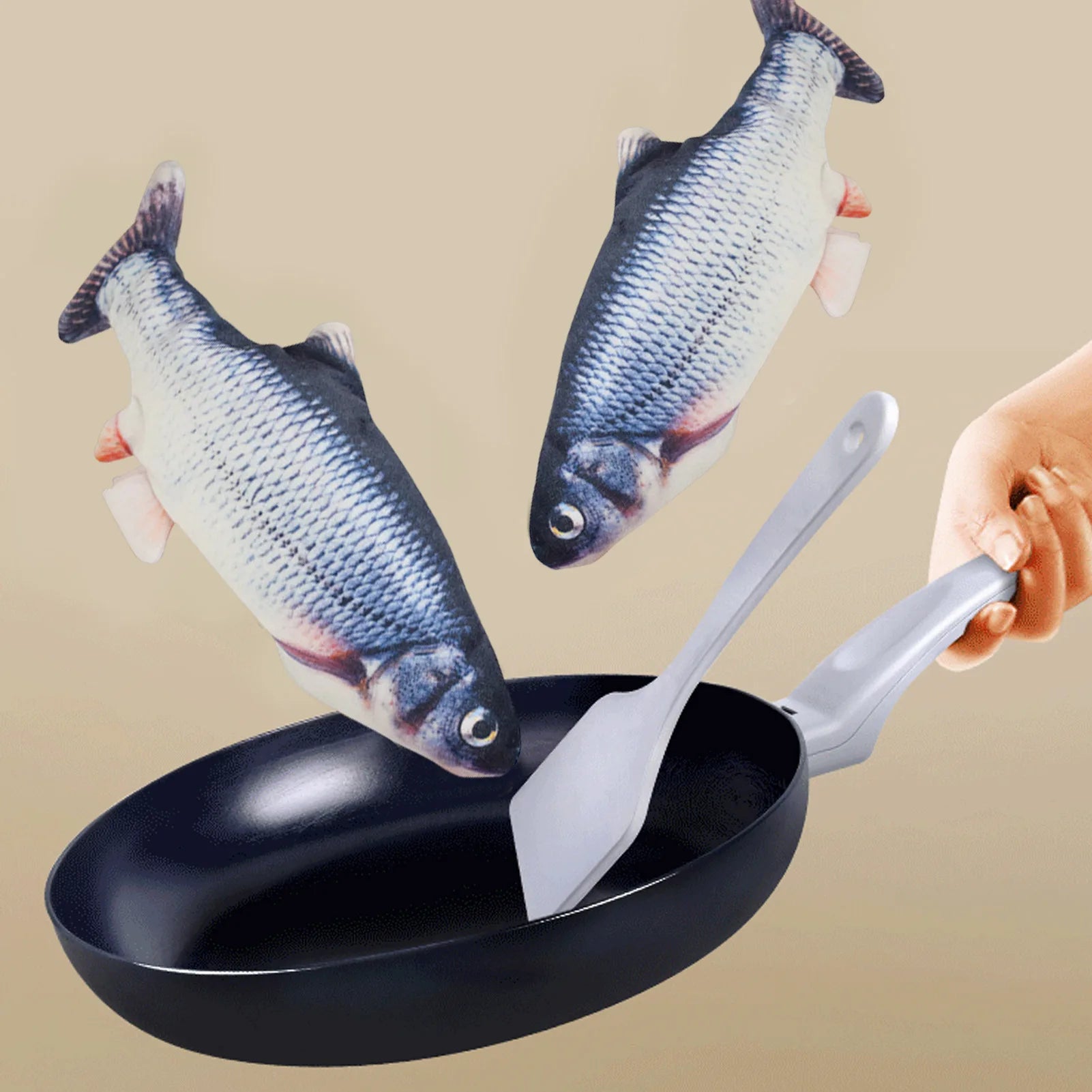 Black frying pan with fish-shaped potholders and a spatula on a beige background