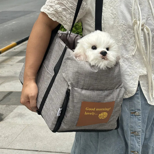 Small white dog in a gray pet carrier with 'Good morning! lovely...' text on a person's shoulder.