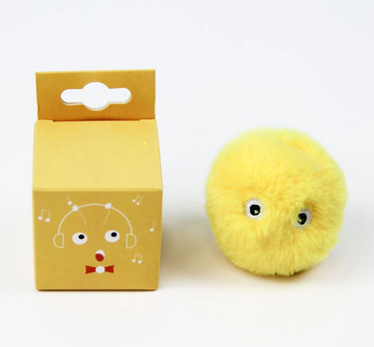 Yellow plush toy with googly eyes next to its packaging on a white background