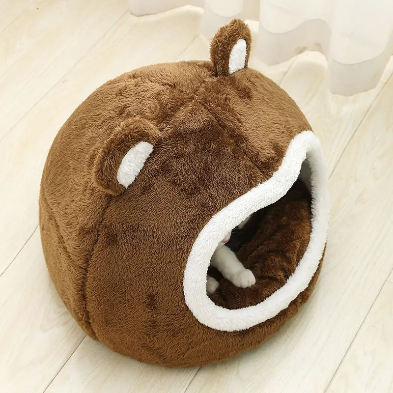 Brown plush pet bed with white accents on a light wooden floor.