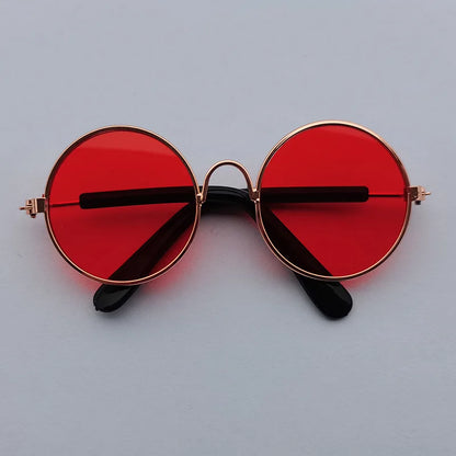 Round sunglasses with red lenses and gold frames on a light gray background