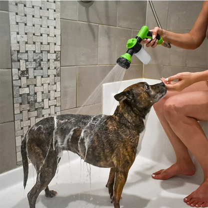 Dog being bathed with a handheld shower head in a tiled bathroom.