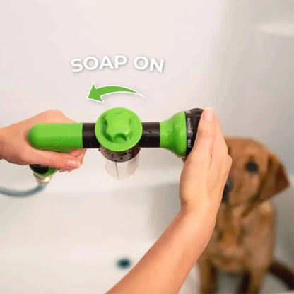 Person using a green pet shower head with soap dispenser, dog in the background