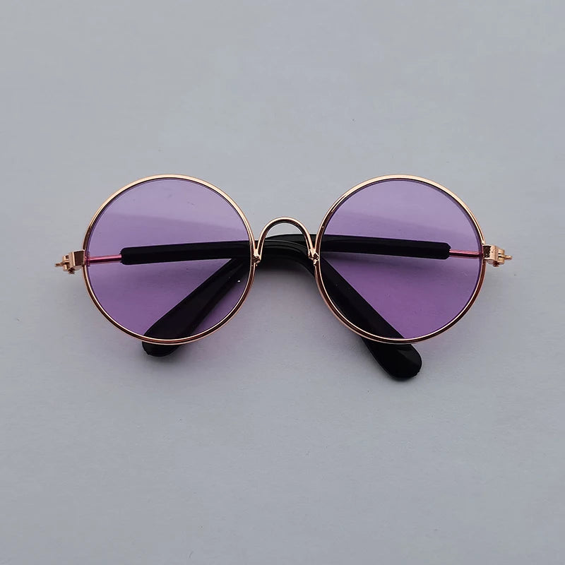 Round sunglasses with purple lenses and gold frames on a gray background