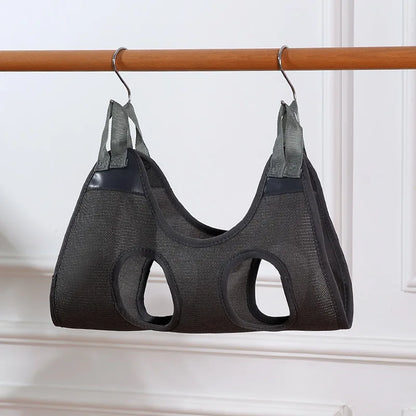 Black mesh pet carrier hanging on a wooden rod against a white wall.