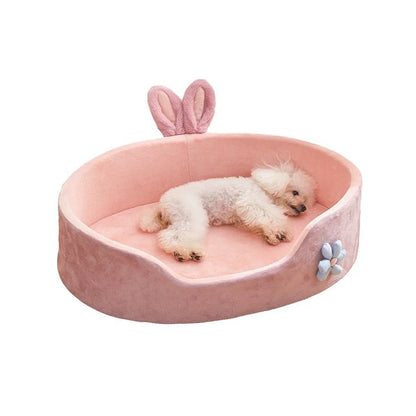 Pink pet bed with bunny ears and a flower design, featuring a small white dog.