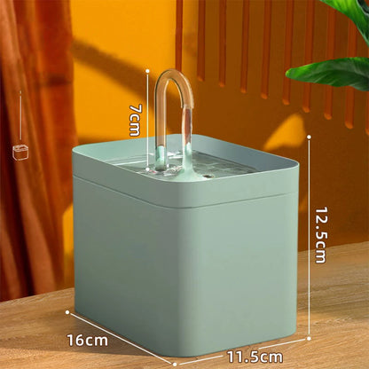 Green pet water fountain with dimensions on a wooden surface and orange curtain background