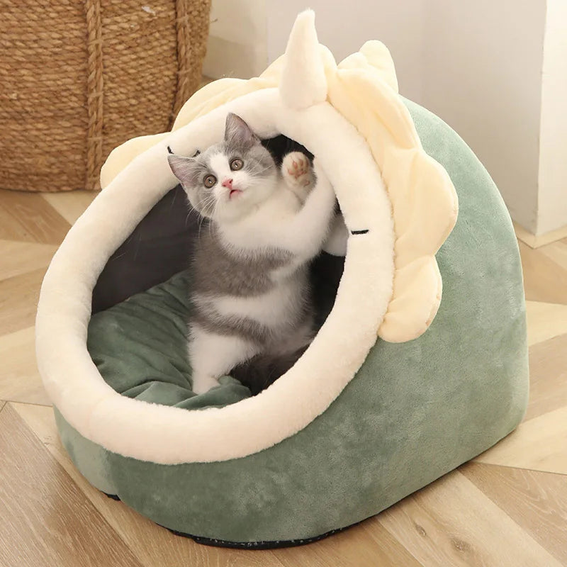 Cat inside a green pet bed with bunny ears on a wooden floor.