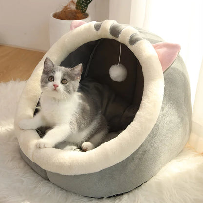 Cat lying in a gray pet bed with pink accents on a soft surface.