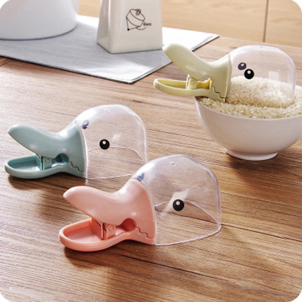 Three cartoon-style duck clips on a wooden surface with a bowl of rice in the background.