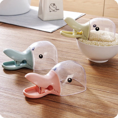 Three cartoon-style duck clips on a wooden surface with a bowl of rice in the background.