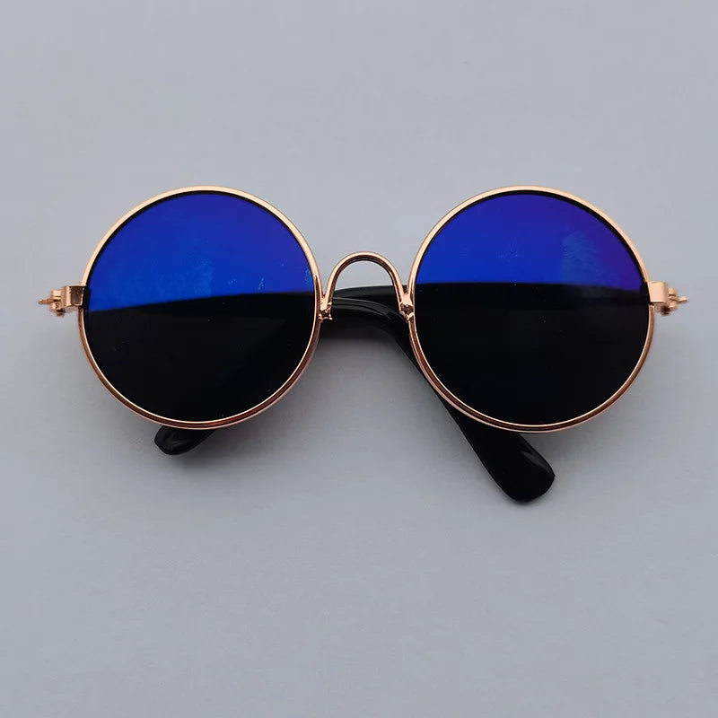 Round sunglasses with blue lenses and gold frame on a gray background