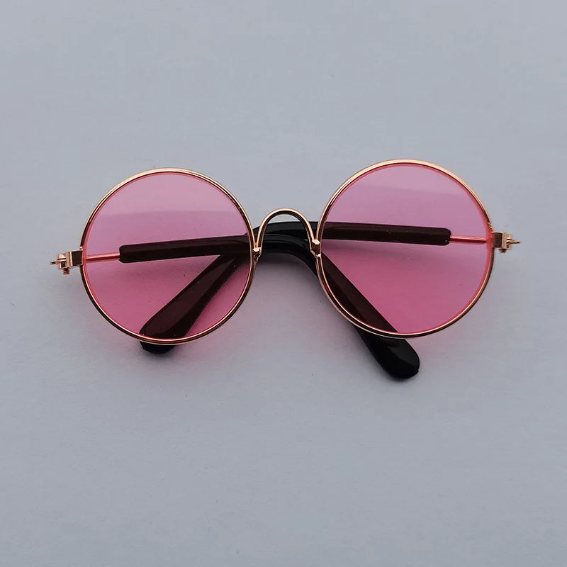Round sunglasses with pink lenses and gold frames on a light gray background