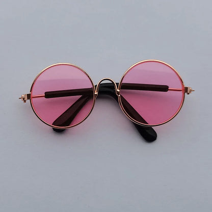 Round sunglasses with pink lenses and gold frames on a light gray background