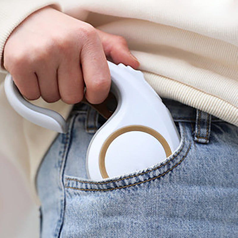 Hand holding a white handheld steamer over jeans