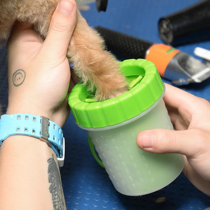 Person holding a green pet cup with a small dog inside, on a blue surface.
