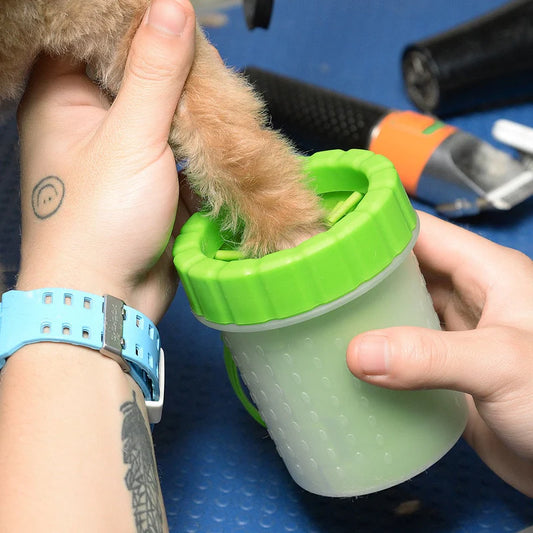 Person holding a green pet cup with a small dog inside, on a blue surface.